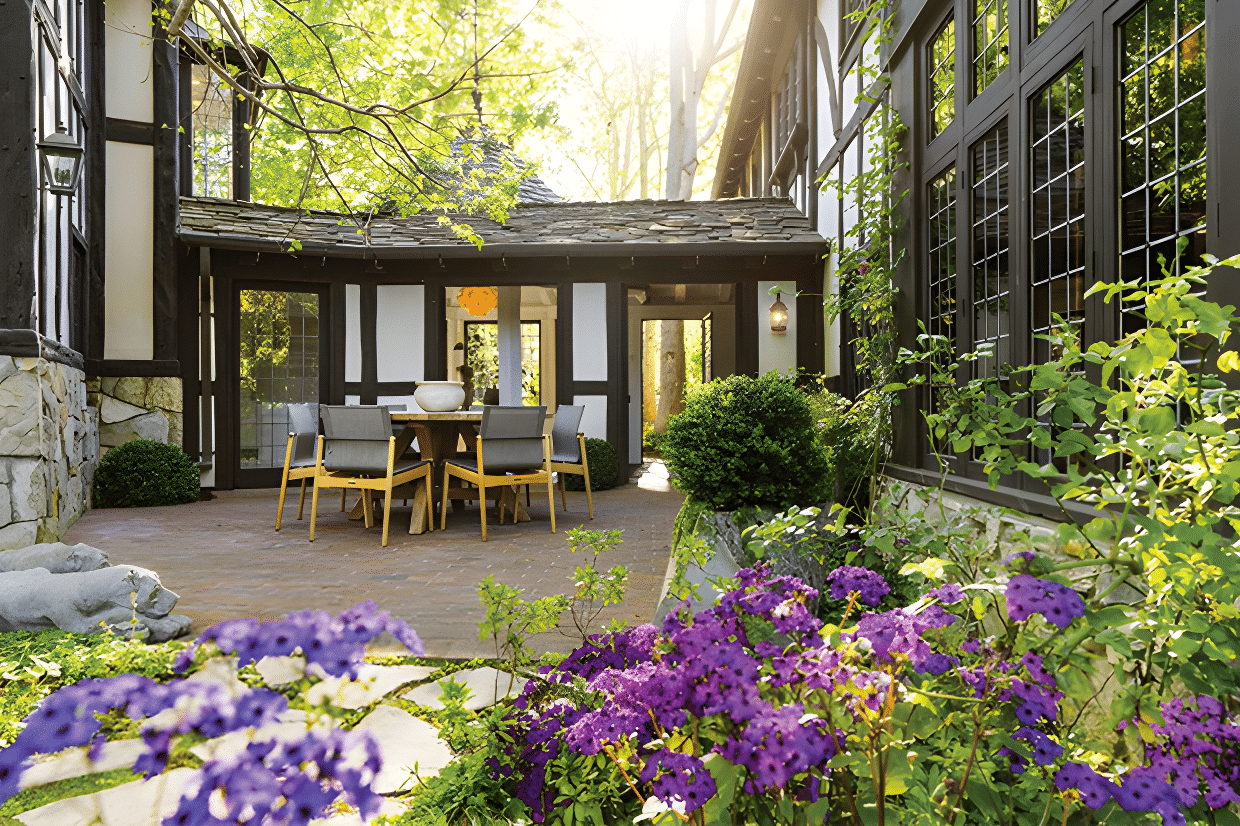 A backyard with about three chairs surrounded by the purple flower and green shrubs.