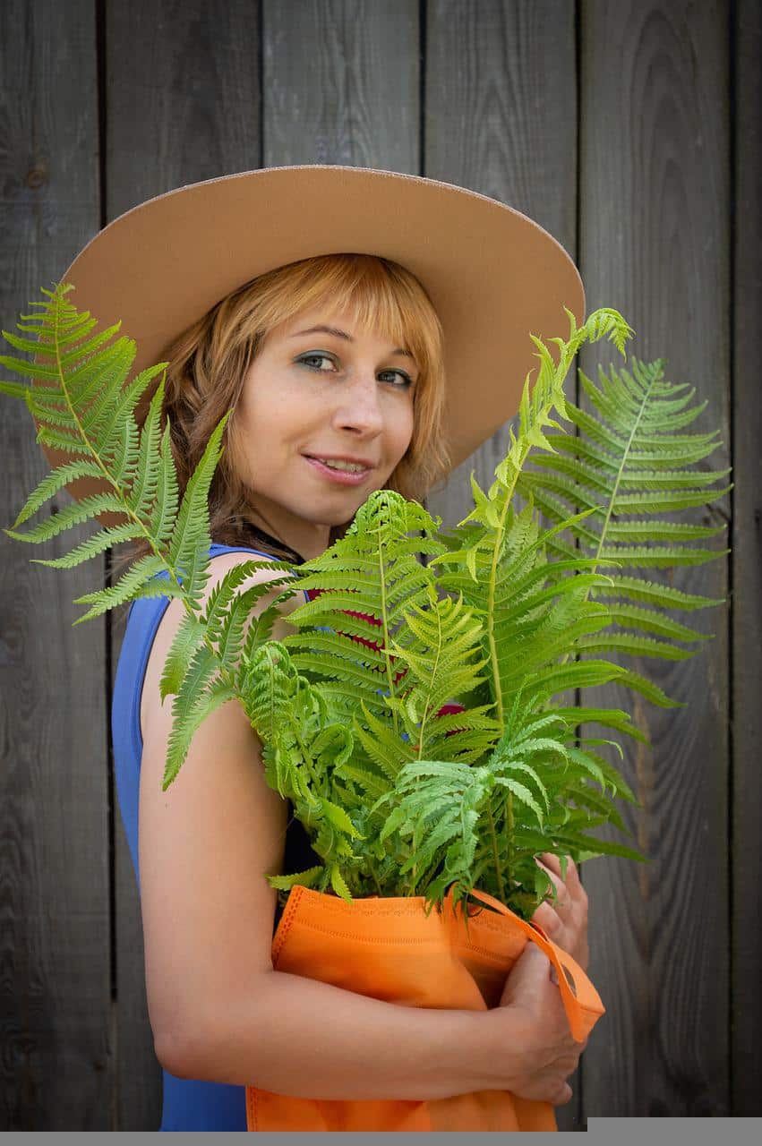 Smiling woman carrying plant