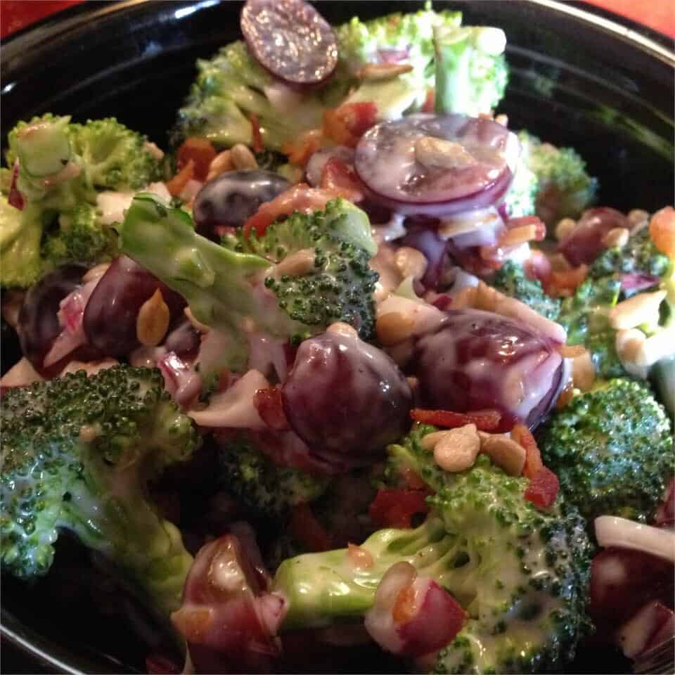 A bowl containing onion, brocoli and sunflower seed crumbs over a table.