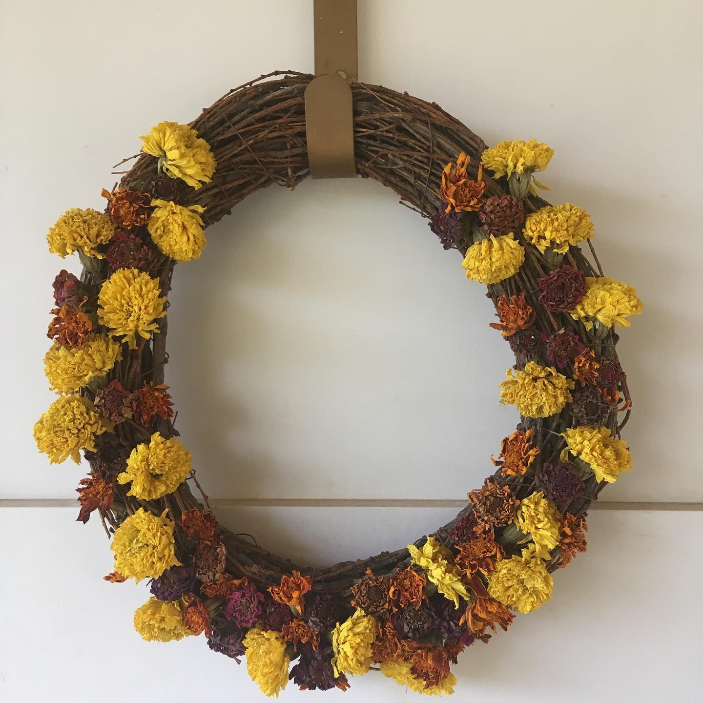 Image represents wreath prepared from the dried blooms and vines of Zinnia and Marigolds