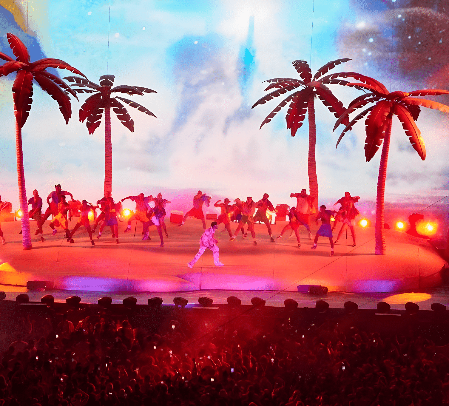 A stage filled with palm tree where Bad bunny is singing with a group of people