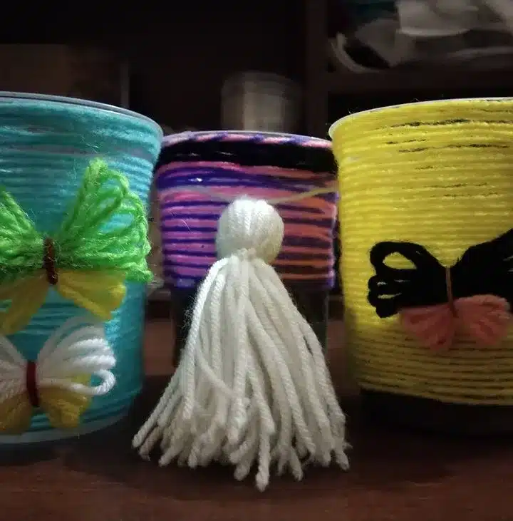 Ceramic pot decor from white, yellow, blue and green yarn